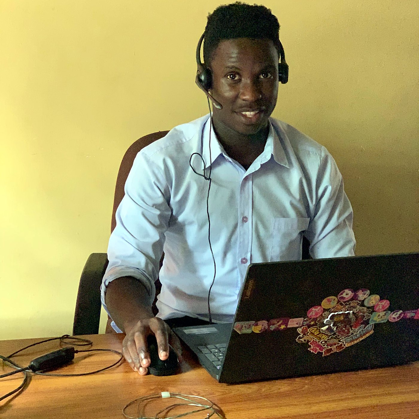 Joshua Kakembo working at a laptop with a headset